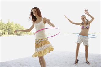 Young women hula hooping on beach. Date : 2008