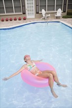 Girl relaxing on inflatable ring in swimming pool. Date : 2008
