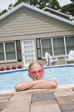 Girl leaning on edge of swimming pool. Date : 2008
