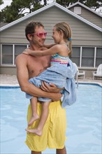 Father holding daughter by swimming pool. Date : 2008