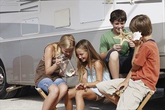 Children looking at seashell collection by motor home. Date : 2008