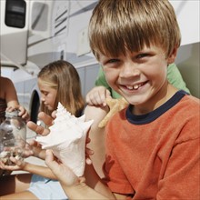 Children looking at seashell collection by motor home. Date : 2008