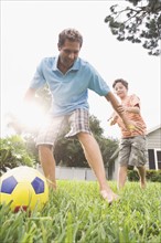 Father and son playing soccer in backyard. Date : 2008