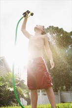 Boy spraying himself with garden hose. Date : 2008