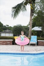 Girl standing at edge of swimming pool with inflatable ring. Date : 2008