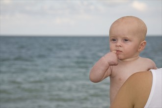 Mother holding baby boy at beach. Date : 2008
