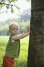 Baby boy leaning against tree. Date : 2008