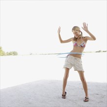 Young woman hula hooping on beach. Date : 2008