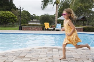 Girl running beside swimming pool. Date : 2008