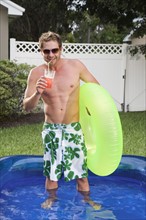 Man standing in inflatable swimming pool. Date : 2008