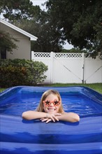 Girl leaning on edge of inflatable swimming pool. Date : 2008