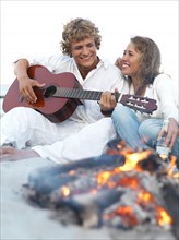 Young couple relaxing by campfire on beach. Date : 2008