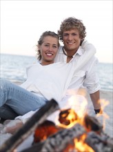 Young couple hugging by campfire on beach. Date : 2008