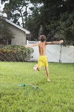 Boy running through sprinklers. Date : 2008