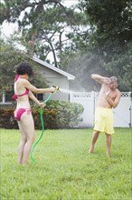 Woman spraying man with hose in backyard. Date : 2008