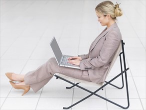 Businesswoman working on laptop in modern chair. Date : 2008