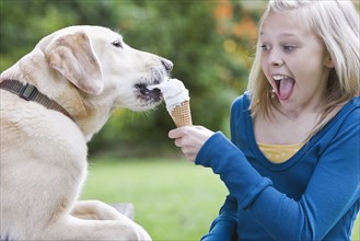 Dog eating girl’s ice cream cone. Date : 2008