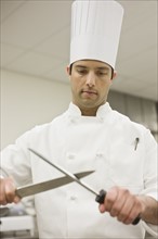 Chef sharpening knife in kitchen. Date : 2008