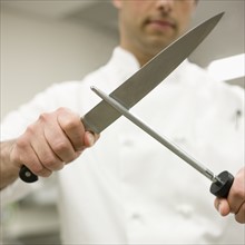 Chef sharpening knife in kitchen. Date : 2008