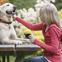 Girl petting dog sitting on picnic table. Date : 2008