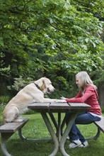 Dog sitting across from girl on picnic table. Date : 2008