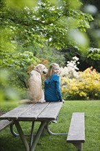 Girl and dog sitting on park bench. Date : 2008