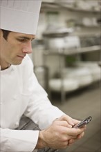 Chef in uniform checking text messages. Date : 2008