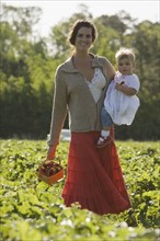 Mother and baby daughter picking strawberries. Date : 2008