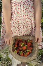 Girl carrying strawberries in straw hat. Date : 2008