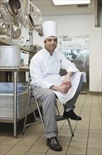 Chef sitting on stool in kitchen. Date : 2008