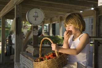 Girl eating fresh strawberries at farm stand. Date : 2008