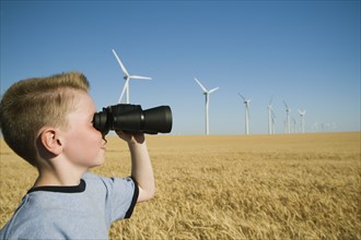 Boy on wind farm looking through binoculars. Date : 2008