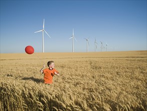 Boy running with balloon on wind farm. Date : 2008