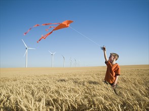 Boy running with kite on wind farm. Date : 2008