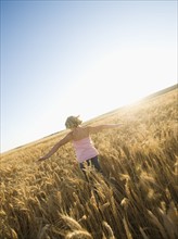 Girl running through tall wheat field. Date : 2008