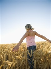 Girl walking through tall wheat field. Date : 2008