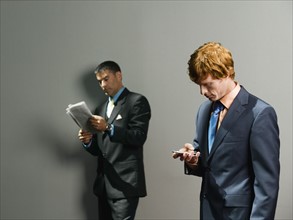 Businessmen holding newspaper and cell phone. Date : 2008