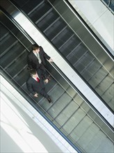 Businessmen descending escalator. Date : 2008