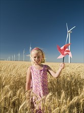 Girl holding pinwheel on wind farm. Date : 2008