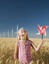 Smiling girl holding pinwheel on wind farm. Date : 2008