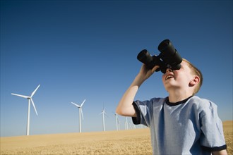 Boy on wind farm looking through binoculars. Date : 2008