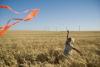 Girl running with kite on wind farm. Date : 2008
