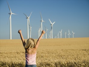 Girl with arms raised on wind farm. Date : 2008
