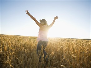 Girl jumping in tall wheat field. Date : 2008