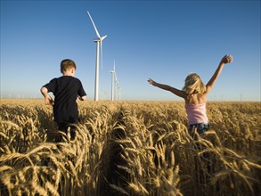 Children running through tall wheat field on wind farm. Date : 2008