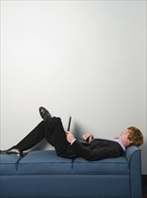 Businessman lounging on sofa with laptop. Date : 2008