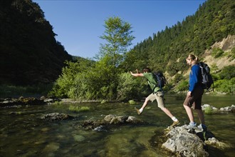 Hikers jumping across river on rocks. Date : 2008
