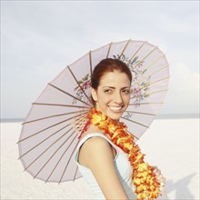 Young woman posing on beach with lei and umbrella. Date : 2008