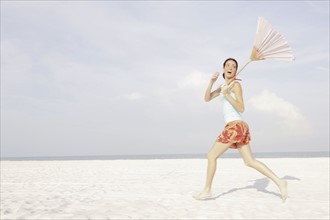 Girl running on beach with umbrella. Date : 2008