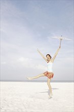 Girl holding umbrella and dancing on beach. Date : 2008